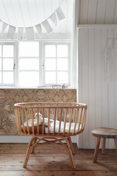 Zimmeransicht mit einem Babybett aus Rattan, einem Fenster und einer Dekoration.