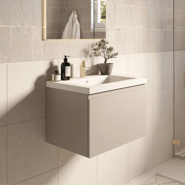 Moderner wandhängender Waschtischunterschrank mit weißem Waschbecken und goldener Armatur vor einer gefliesten Wand in einem hellen Badezimmer.