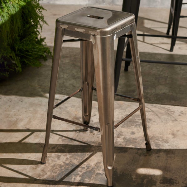 Barhocker aus Metall im Industrial-Design mit quadratischer Sitzfläche und Griffloch auf einem Betonboden.