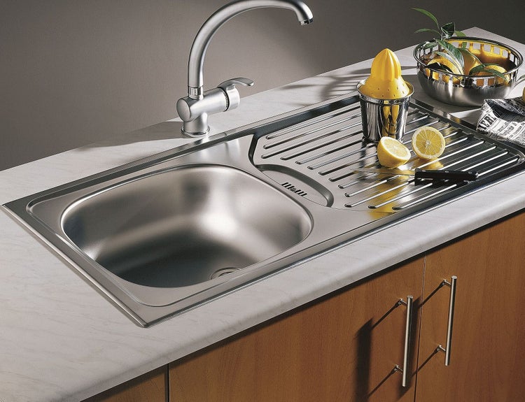 Edelstahlspüle mit Abtropffläche und Armatur auf einer Arbeitsplatte