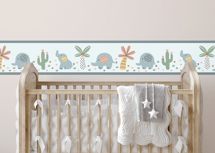 Selbstklebende Tapetenborte mit Elefanten, Palmen und Kakteen im Kinderzimmer über einem hölzernen Babybett.