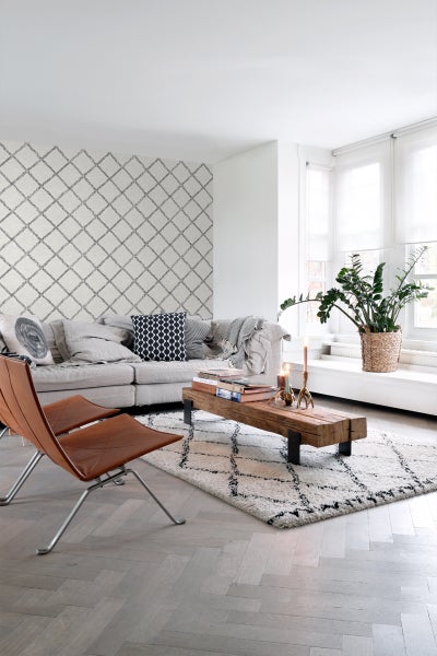 Heller Wohnraum mit Sofa, Sessel, Holztisch und gemusterter Tapete