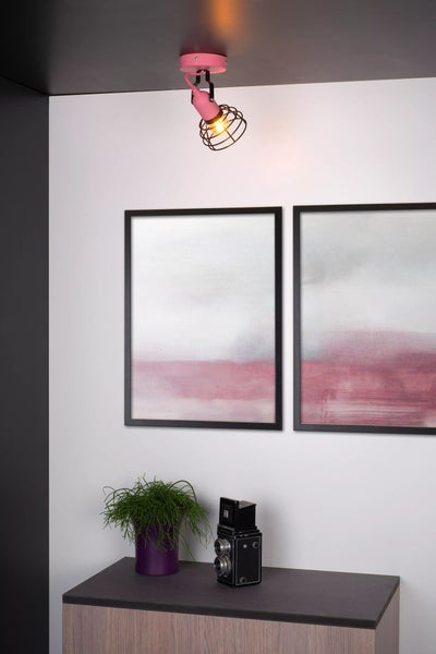 Wohnraum mit rosa Deckenstrahler, Bildern und Dekoration auf einer Kommode