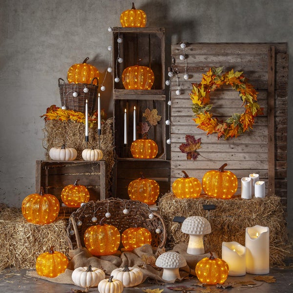 Dekorative Herbstszene mit leuchtenden Kürbissen, Heuballen, herbstlichen Blättern, Kerzen und Holzkisten