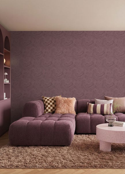 Wohnzimmer mit Ecksofa, Kissen, Couchtisch und Bücherregal