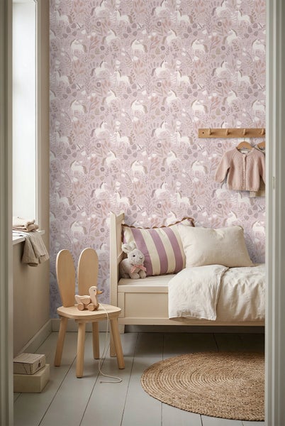 Helles Kinderzimmer mit Einhorn-Tapete, Holzbett, Stuhl mit Hasenohren-Rückenlehne und rundem Jute-Teppich.