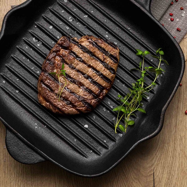 Ein Steak in einer Grillpfanne mit Kräutern und Salz