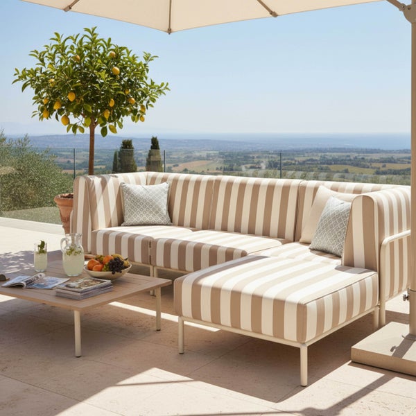 Modulares Garten-Lounge-Set bestehend aus gestreiftem Ecksofa, Hocker und Couchtisch auf einer hellen Terrasse mit Ausblick.