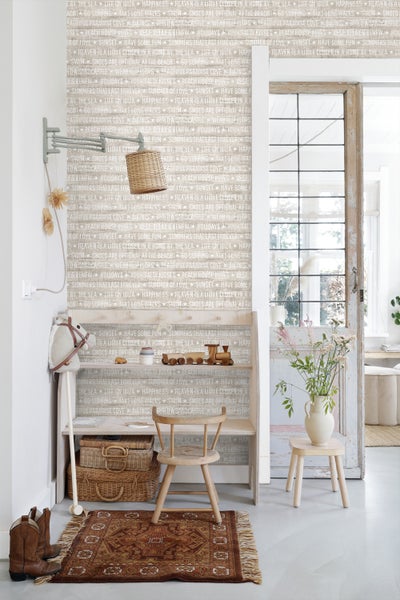 Szene mit einer Bank, einem Stuhl, einem Teppich und Dekorationsgegenständen in einem Raum mit bedruckter Tapete