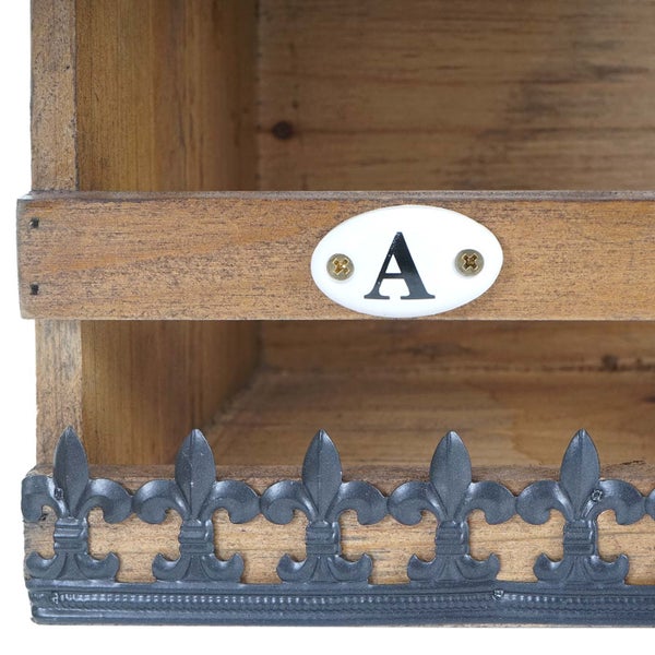 Detailansicht eines Holzregals mit dekorativer Bordüre und einem Schild mit dem Buchstaben A.
