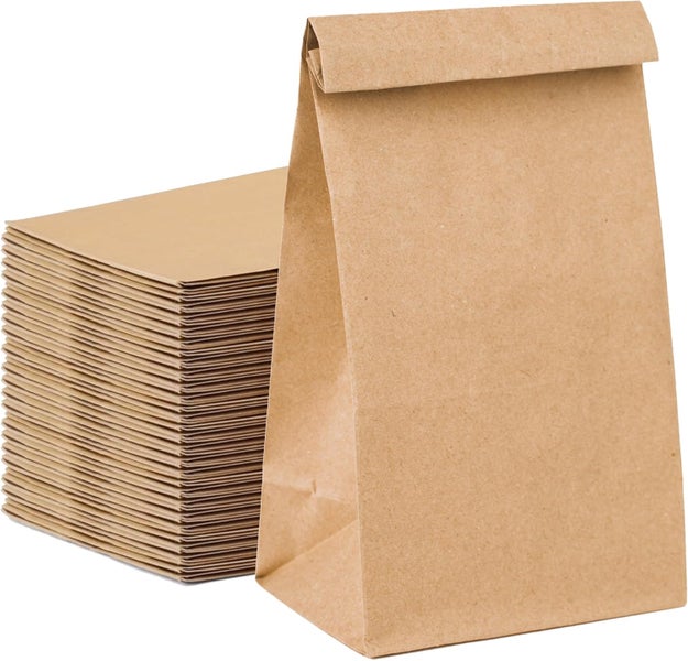 Braune Papiertüten, eine steht aufrecht, daneben ein Stapel flach liegender Tüten