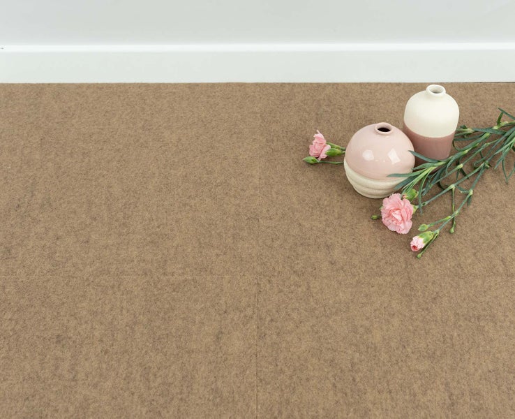 Strukturierte Teppichfliesen aus Filz auf einem Boden neben einer Fußleiste, dekoriert mit Keramikvasen und Blumen.