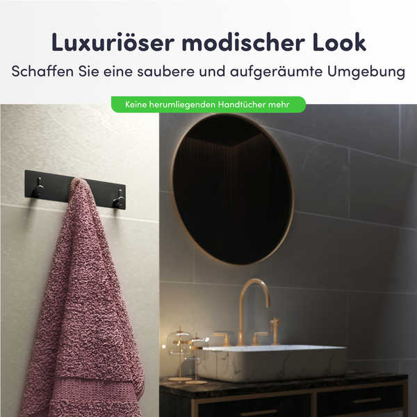 Schwarze Handtuchhakenleiste mit zwei Haken an einer hellen Fliesenwand in einem modern eingerichteten Badezimmer mit Marmorwaschbecken.