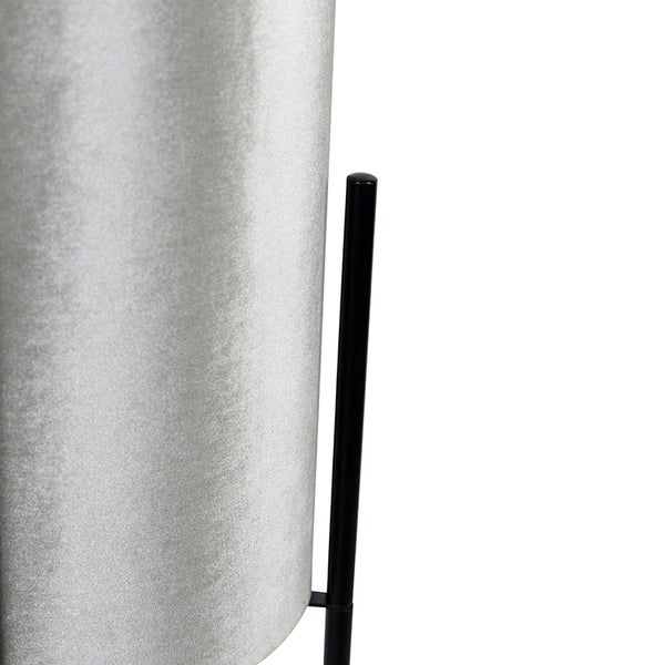 Nahaufnahme eines zylindrischen Lampenschirms aus schimmerndem Stoff mit einem schwarzen Metallstativ.