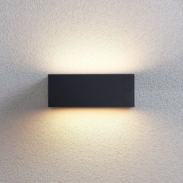 Moderne rechteckige Außenwandleuchte in Schwarz mit Lichtstrahl nach oben und unten an einer strukturierten Wand.