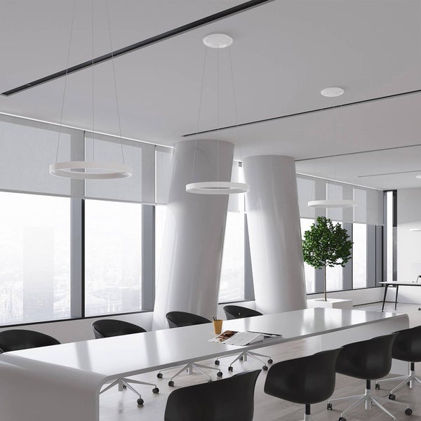 Modernes, helles Konferenzzimmer mit drei ringförmigen LED-Pendelleuchten über einem langen weißen Tisch und schwarzen Bürostühlen.
