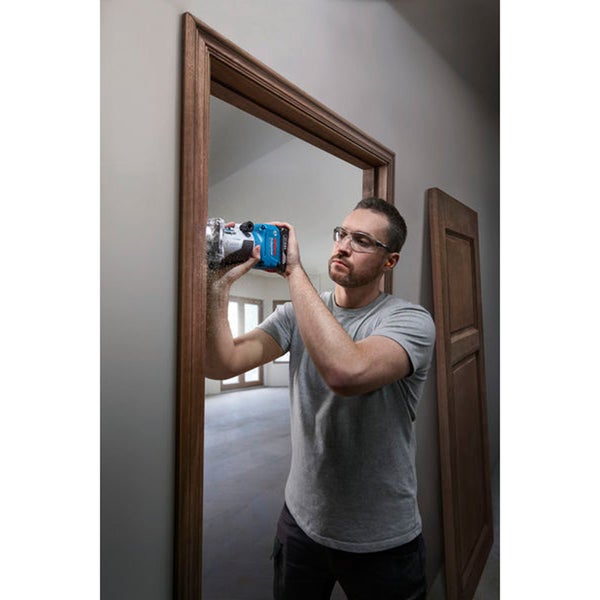 Mann verwendet eine Oberfräse an einem Türrahmen.