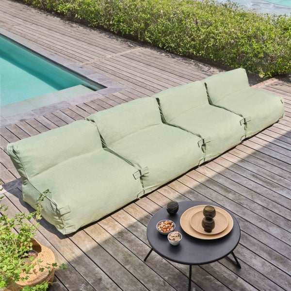 Modernes modulares Outdoor-Lounge-Sofa in Hellgrün auf einer Holzterrasse neben einem Pool, mit einem kleinen runden Beistelltisch.