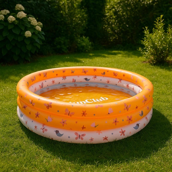 Aufblasbares Kinderplanschbecken mit drei Ringen und Schmetterlingsprint in einem grünen Garten auf dem Rasen.