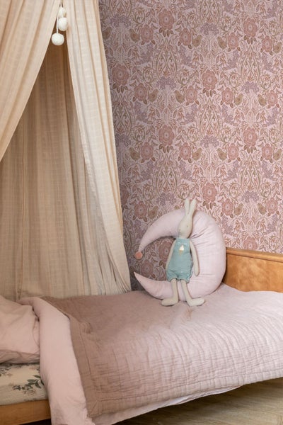 Vliestapete mit Blumen- und Vogelmuster in einem gemütlich gestalteten Kinderzimmer mit Bett, Betthimmel und Mondkissen.