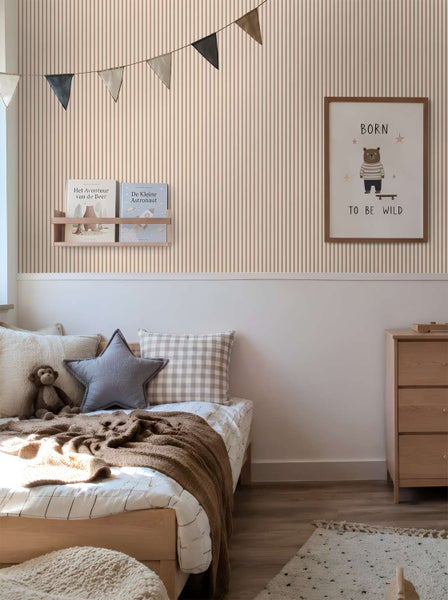 Ein Kinderzimmer mit gestreifter Tapete, Holzmöbeln, Bilderrahmen mit Bär-Motiv, Wimpelkette und Bücherregal an der Wand.