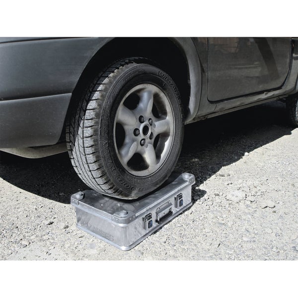 Zarges Aluminiumkiste unter einem Autoreifen als Auffahrrampe zur Höhenausrichtung bei Wohnmobilen oder Fahrzeugen auf unebenem Gelände