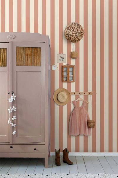 Dekoratives Kinderzimmer mit gestreifter Tapete, Kleiderschrank, Kinderkleidung und Accessoires.