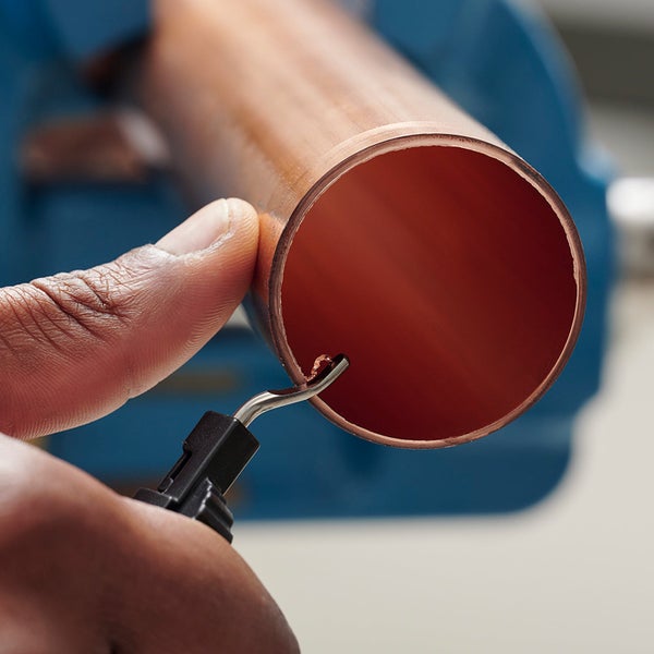 Anwendung eines Entgraters an der Innenkante eines Kupferrohrs.