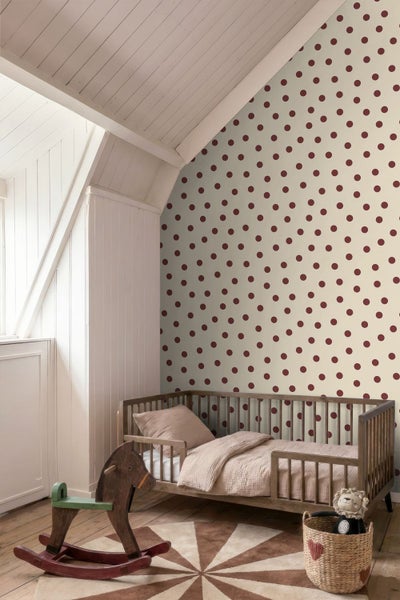 Vliestapete mit Punktmuster in einem Kinderzimmer mit Holz-Gitterbett und einem Schaukelpferd unter einer Dachschräge.