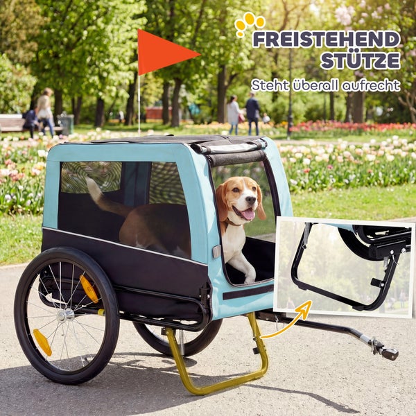 Hellblau-schwarzer Hundefahrradanhänger mit freistehender Stütze, Sicherheitsfahne und einem Beagle im Inneren in einer Parkumgebung.