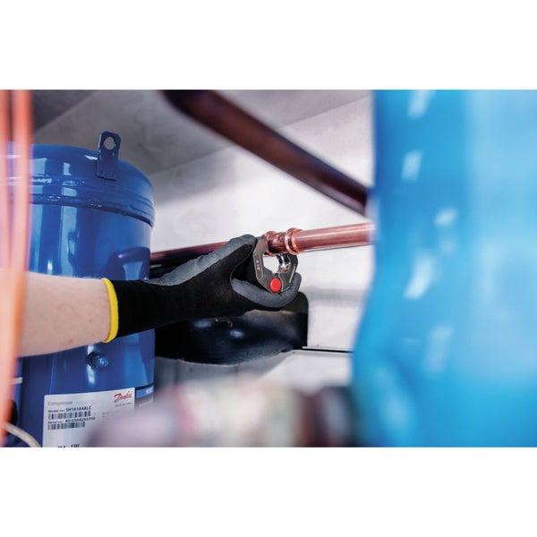 Eine Person verwendet ein Rohrabschneiderwerkzeug, um ein Kupferrohr zu schneiden.