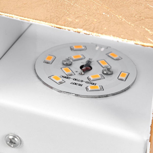 Detailansicht einer Leuchte mit kreisförmigen LED-Chips in einem weißen Gehäuse mit goldfarbener strukturierter Oberfläche.