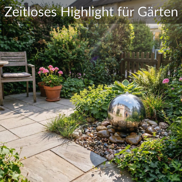 Edelstahl-Kugelfrontäne in einem organisierten Gartenbeet auf Kieselsteinen neben einer Steinterrasse mit Holzstuhl und Pflanzen.