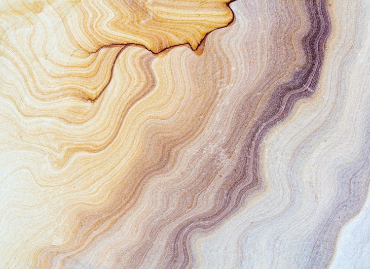 Nahaufnahme einer Natursteinoberfläche in Sandsteinoptik mit wellenförmiger Maserung und natürlicher Struktur.