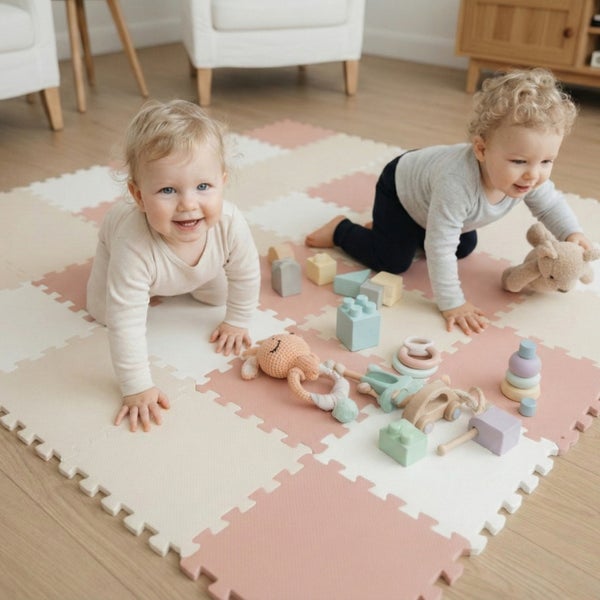 Zwei Kleinkinder spielen auf einer quadratischen Puzzlematte aus Schaumstoff mit verschiedenen Spielzeugen in einem hellen Kinderzimmer.