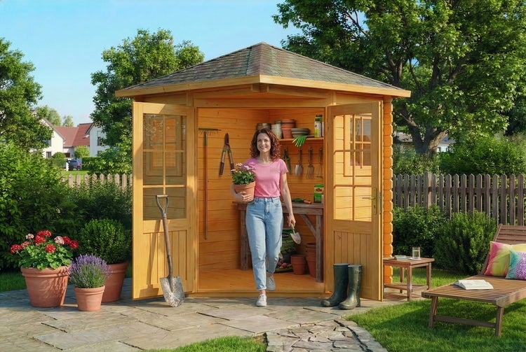 Hölzernes Eck-Gartenhaus mit Doppeltüren in einem Garten, ausgestattet mit Regalen, Gartengeräten und einer Frau mit einer Pflanze.