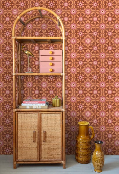 Retro-Vliestapete mit geometrischem Blumenmuster an einer Wand hinter einem Regal aus Bambus und Rattan mit Dekoration und Keramikvasen.