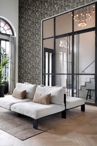 Helles Wohnzimmer mit Sofa, Teppich, gemusterter Tapete und Glastür