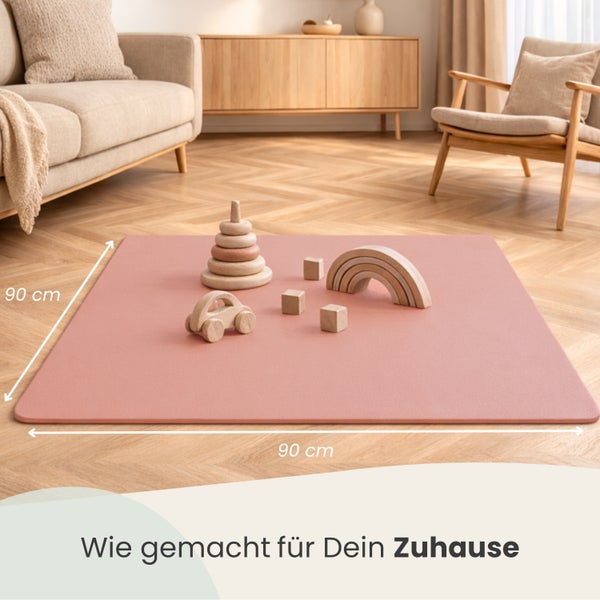 Quadratische Spielmatte, 90 Zentimeter mal 90 Zentimeter, in einem hellen Wohnzimmer mit Holzspielzeug auf Parkettboden.