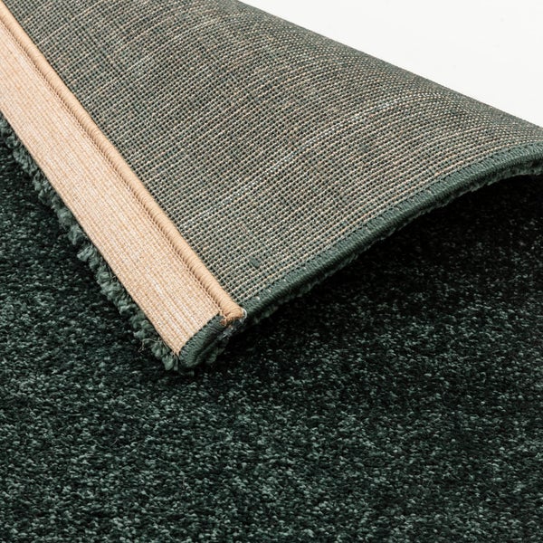 Grüner Hochflor-Teppich mit Detailansicht der gewebten Rückseite und Kettelung.