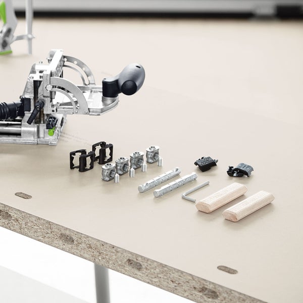 Festool Domino Dübelfräse mit Verbindern, Querankern, Bolzen und Holzdübeln auf einer Werkplatte.