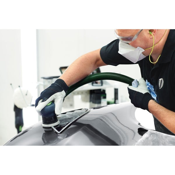 Handwerker schleift mit einem Exzenterschleifer eine Oberfläche, während ein Absaugsystem Staub entfernt.