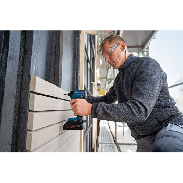 Ein Mann arbeitet mit einem Akku-Bohrschrauber an einer Holzfassade. Er trägt eine Schutzbrille und Ohrstöpsel.