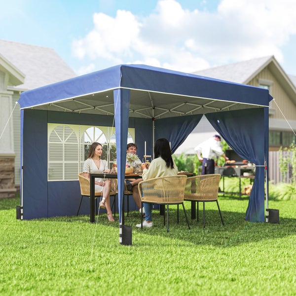 Faltpavillon mit Seitenwänden und Fenstern im Garten, Personen an einem Tisch mit Rattanstühlen, Grill und Haus im Hintergrund.