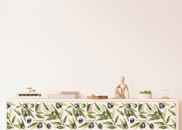 Selbstklebende Möbelfolie mit Olivenzweig-Muster auf einem Sideboard in einem hellen, modernen Raum.