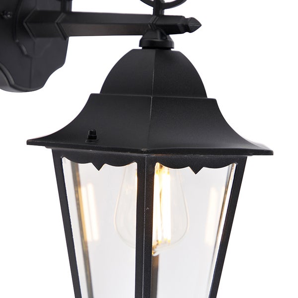 Schwarze Außenwandleuchte im Laternen-Design mit klarem Glas und sichtbarem Leuchtmittel.