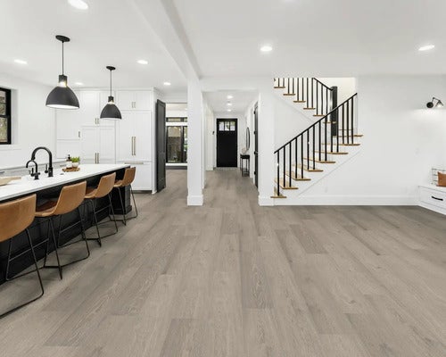 Heller Wohnraum mit grauem Laminatboden, Kücheninsel und Treppe
