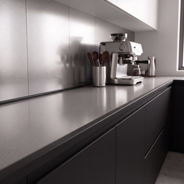 Moderne Küche mit dunklen Fronten und Arbeitsplatte sowie einer metallischen Nischenrückwand und Siebträgermaschine.
