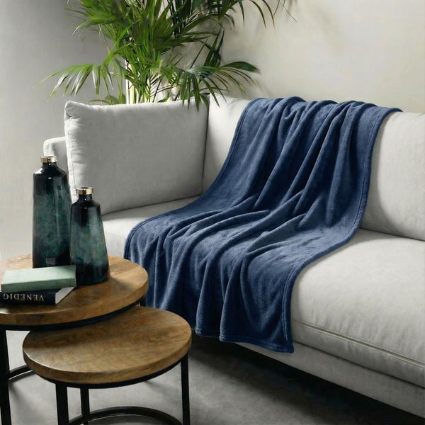 Wohnzimmer-Szene mit Sofa, blauer Kuscheldecke und Beistelltisch mit Dekoration