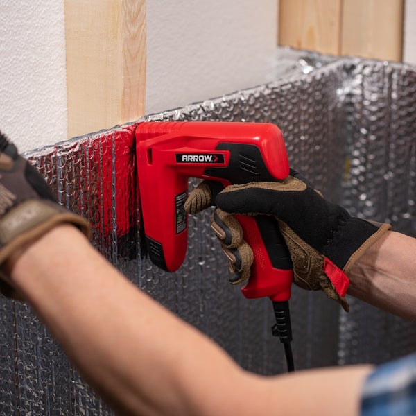 Handwerker befestigt eine reflektierende Isolierfolie mit einem Arrow Elektrotacker an einem Holzständer.